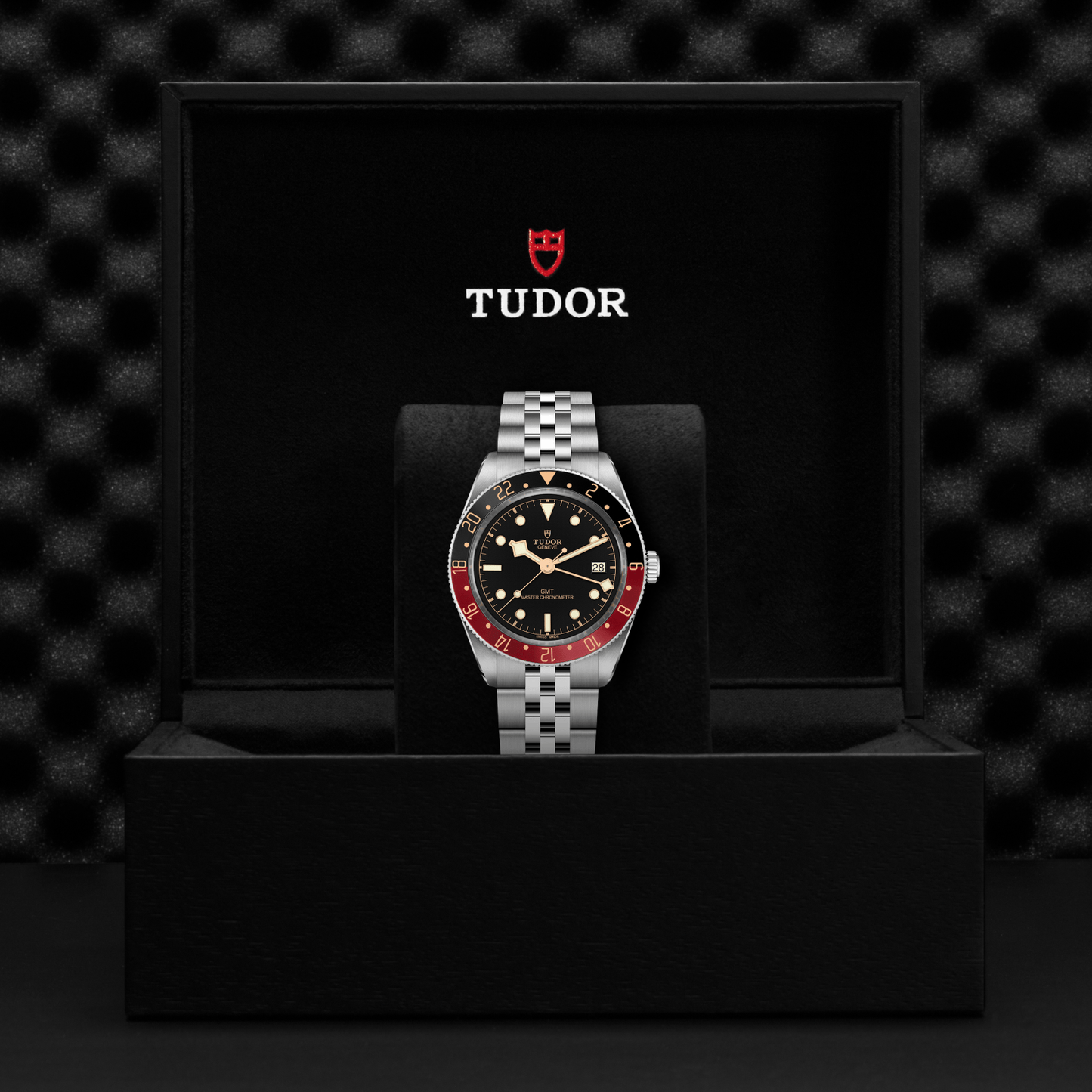 Tudor Black Bay 58 watch with a steel bracelet and black dial in a black box against a black background.