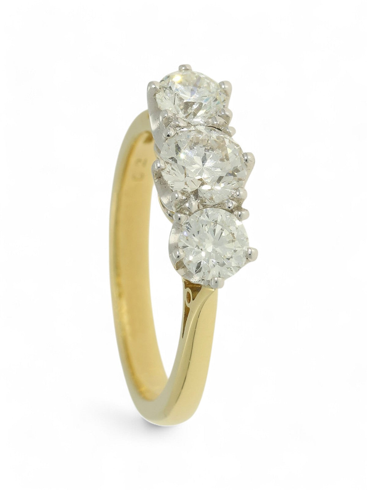 Three stone diamond ring with a yellow gold shank on a white background.