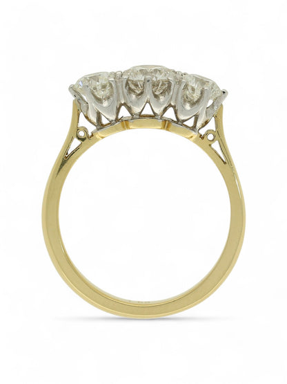 Three stone diamond ring with a yellow gold shank on a white background.