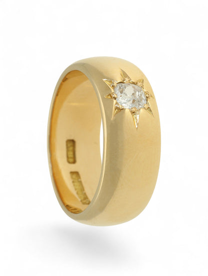 18ct yellow gold wide band ring with a single diamond in a star setting on a white background.