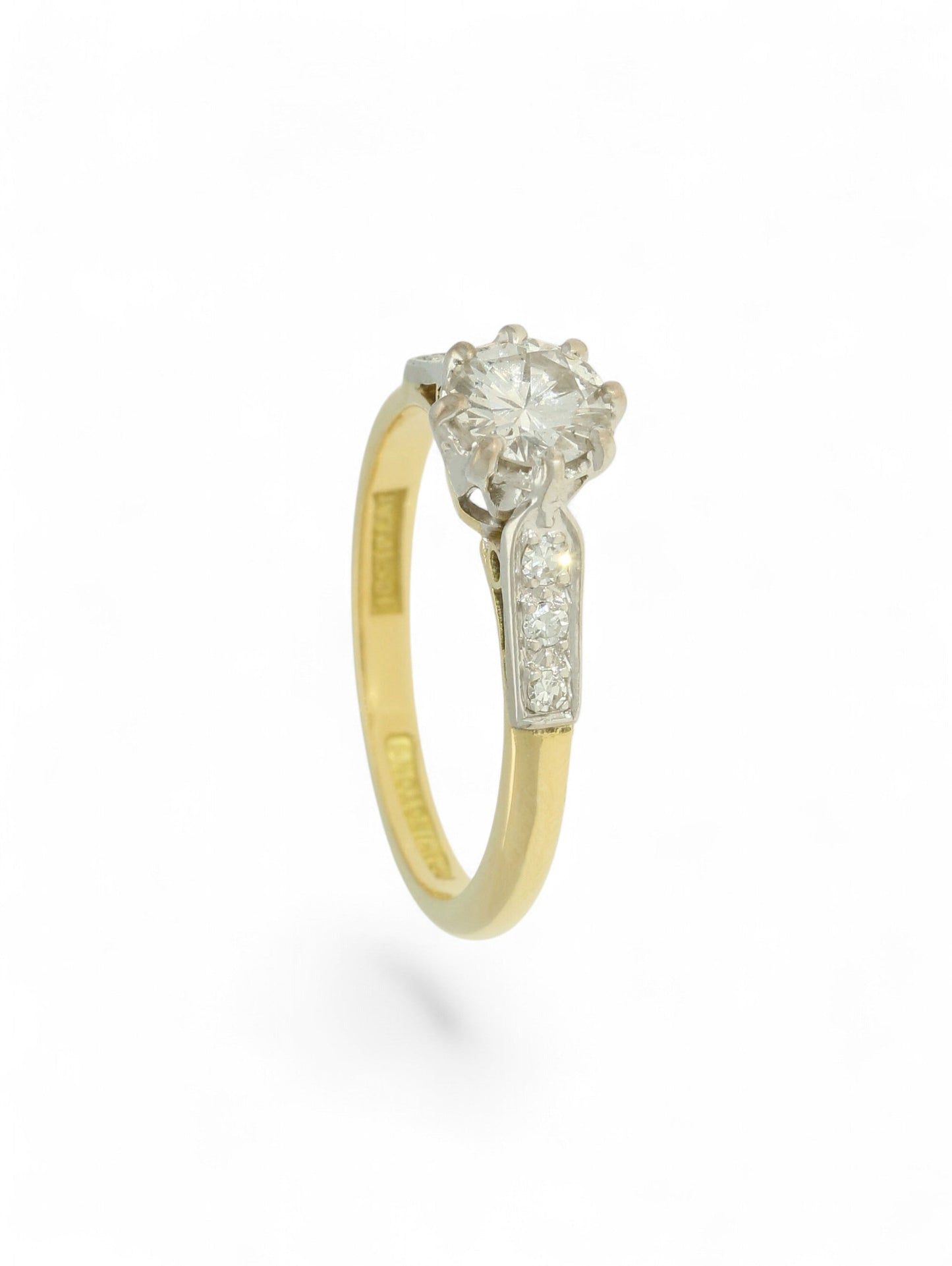 Diamond single stone ring with an eight-claw platinum setting, yellow gold band, and diamond-set shoulders.