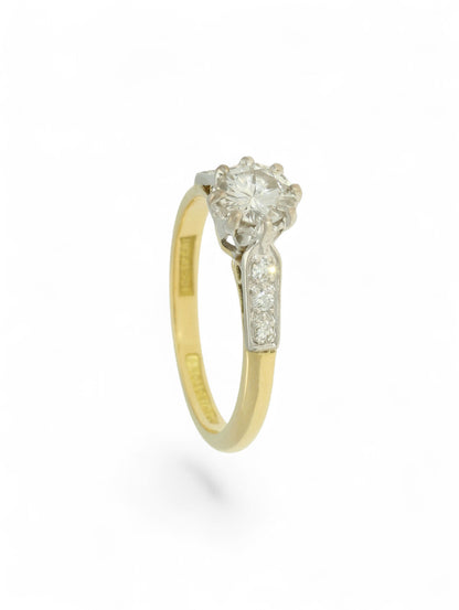 Diamond single stone ring with an eight-claw platinum setting, yellow gold band, and diamond-set shoulders.