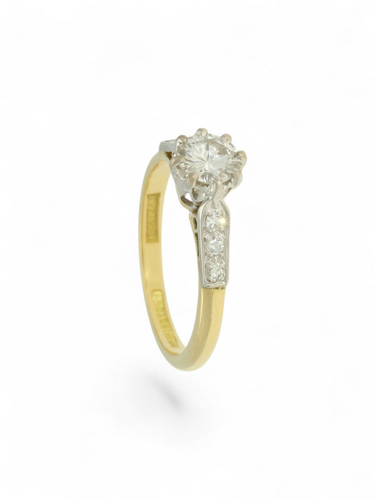 Diamond single stone ring with an eight-claw platinum setting, yellow gold band, and diamond-set shoulders.
