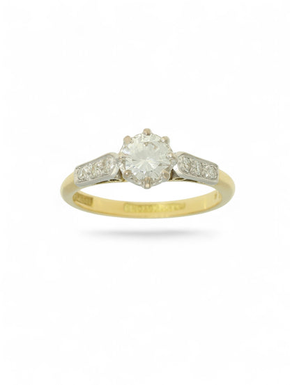 Diamond single stone ring with an eight-claw platinum setting, yellow gold band, and diamond-set shoulders.