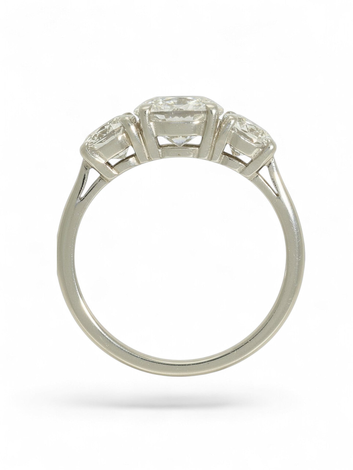 Platinum three-stone diamond ring with oval-cut centre and two round brilliant-cut stones on a white background.