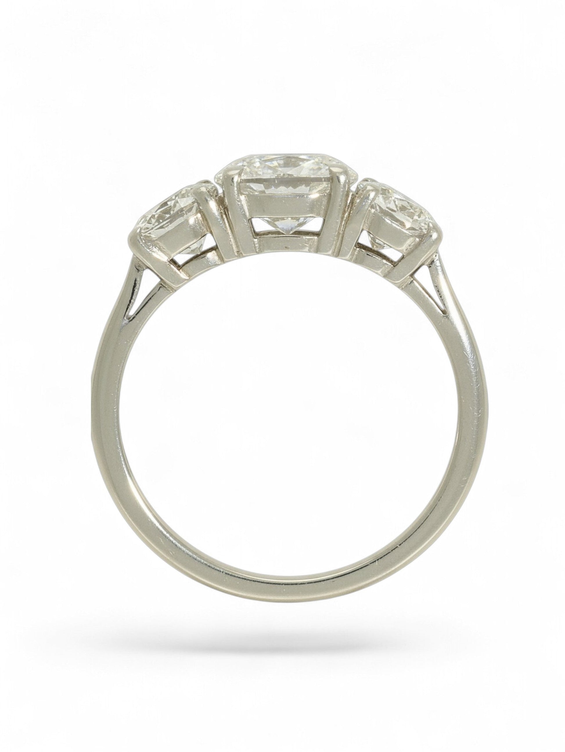 Platinum three-stone diamond ring with oval-cut centre and two round brilliant-cut stones on a white background.
