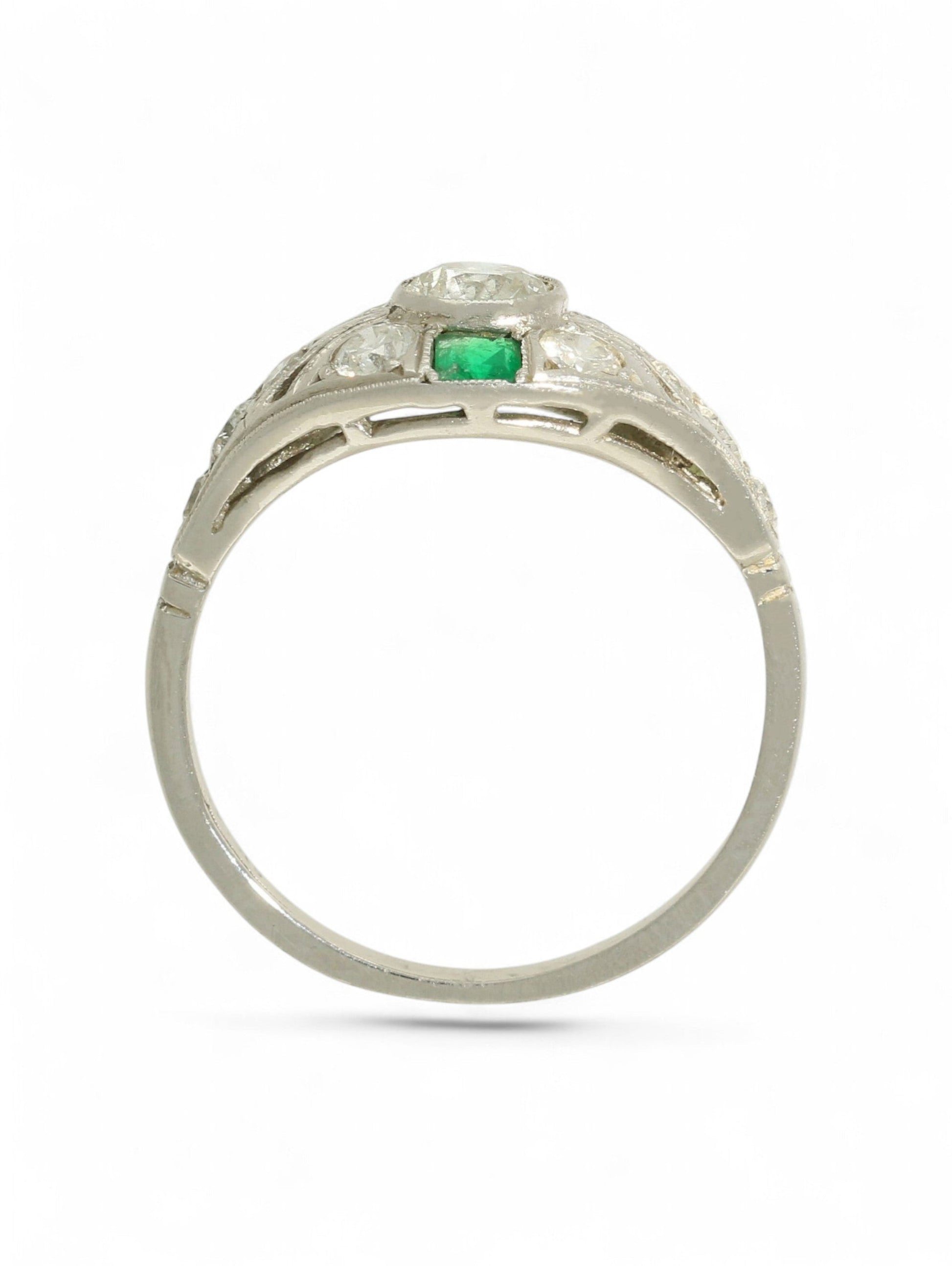 Platinum art deco-style ring with round-cut diamonds and square-cut emeralds on a white background.