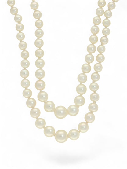 Two strands of white pearls on a white background