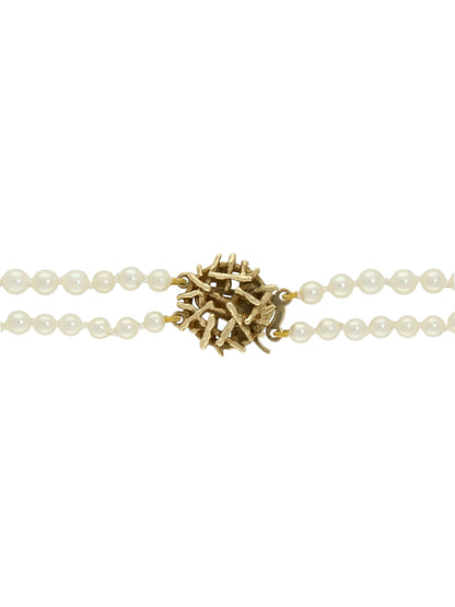 Yellow gold clasp attached to two strands on white pearls on a white background.