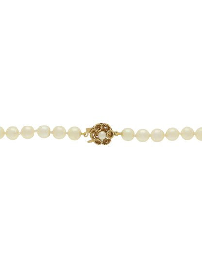 Single strand of white pearls with knot clasp on a white background.