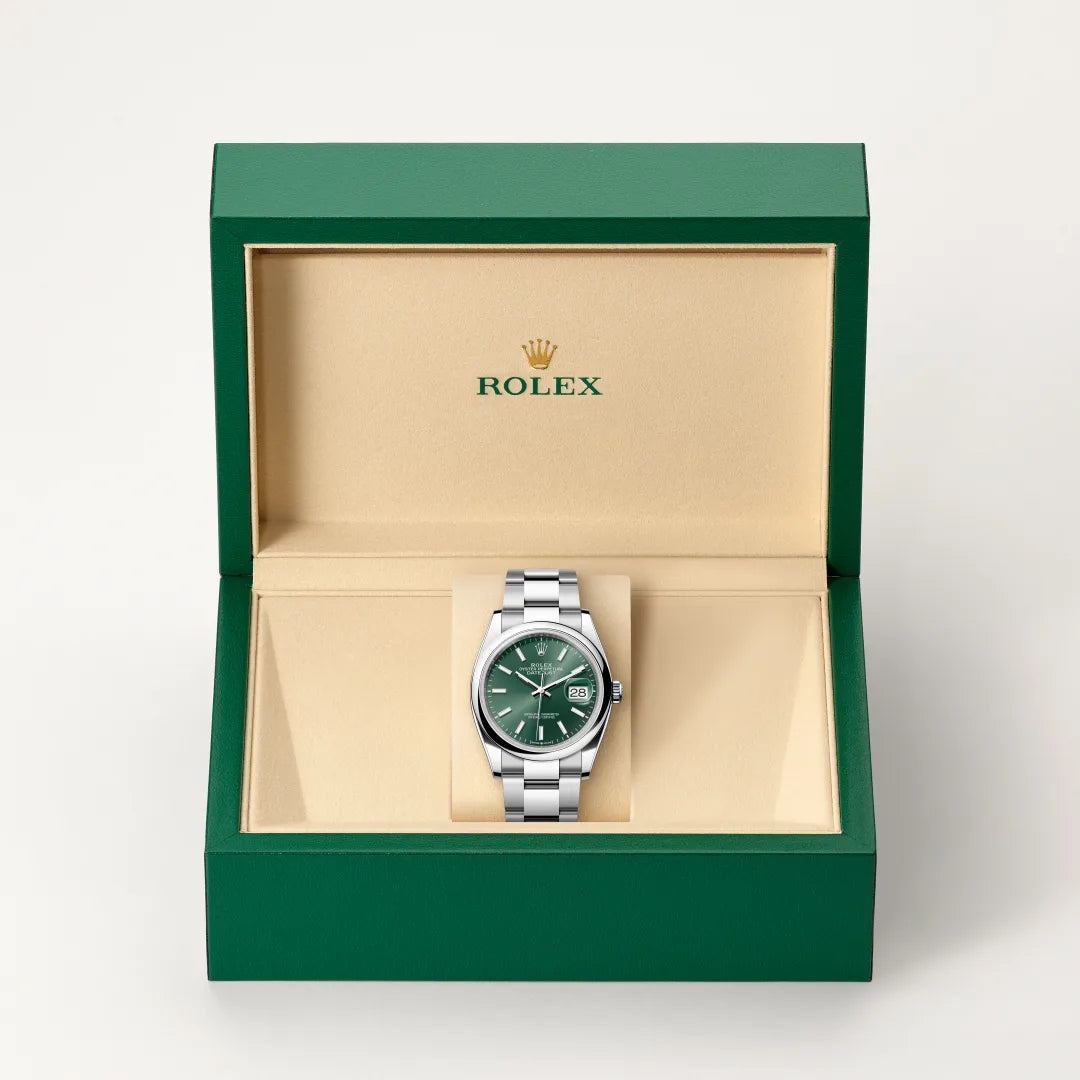 Rolex Datejust watch in a green and beige presentation box on a light background.