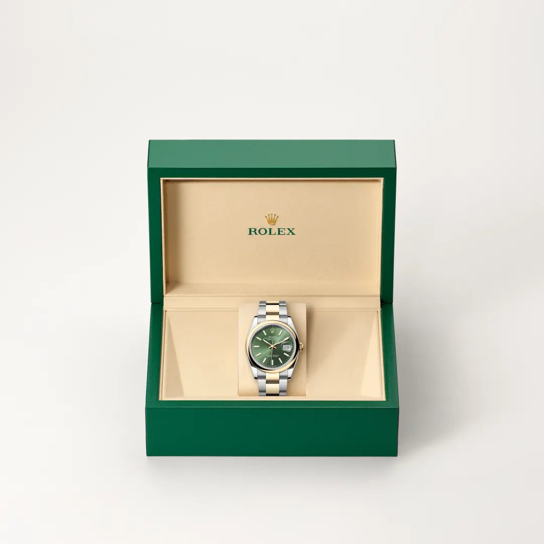 Rolex Datejust watch in a green and beige presentation box on a light background.