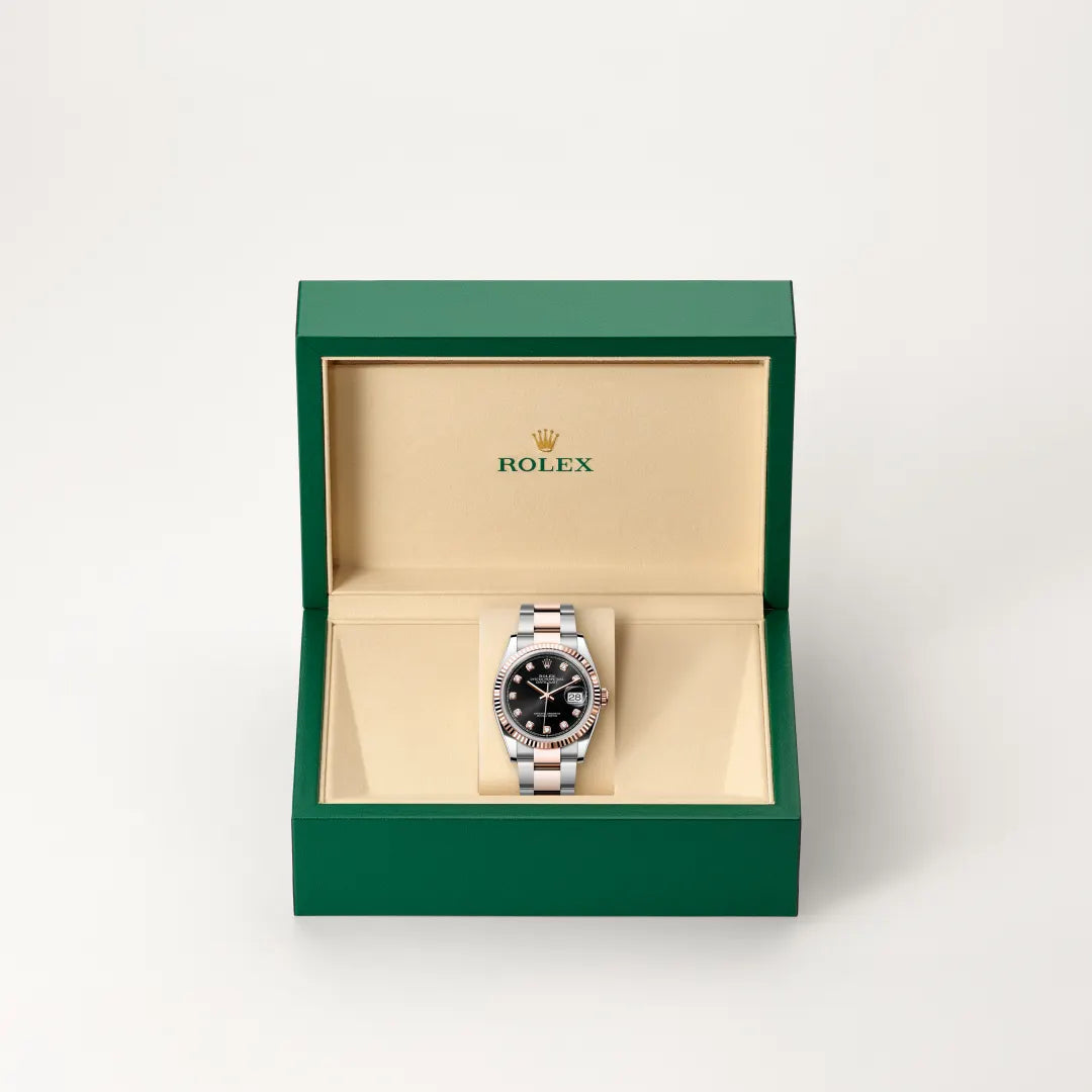 Rolex Datejust watch in a green and beige presentation box on a light background.
