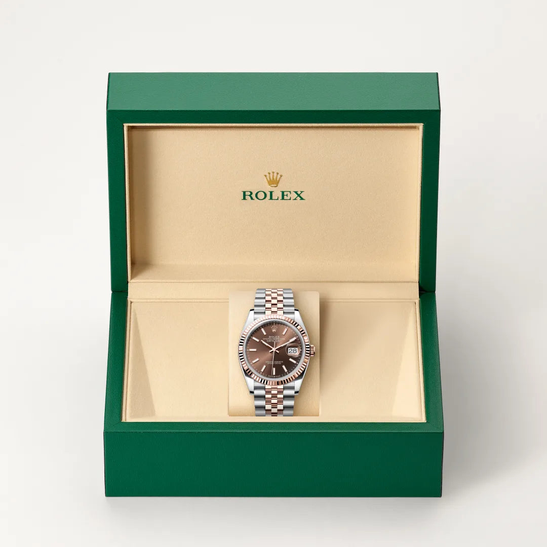 Rolex Datejust watch in a green and beige presentation box on a light background.