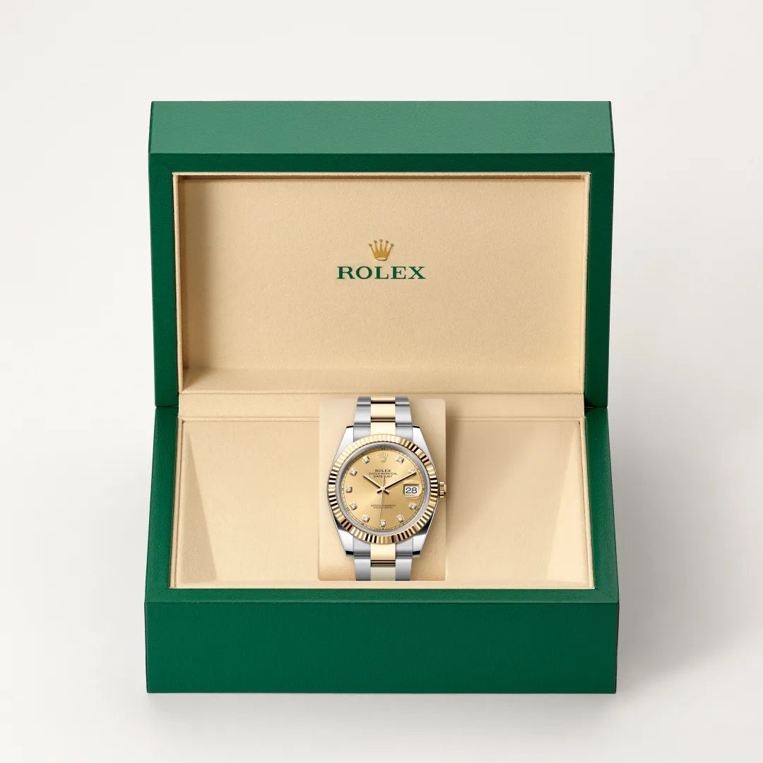 Rolex Datejust watch in a green and beige presentation box on a light background.