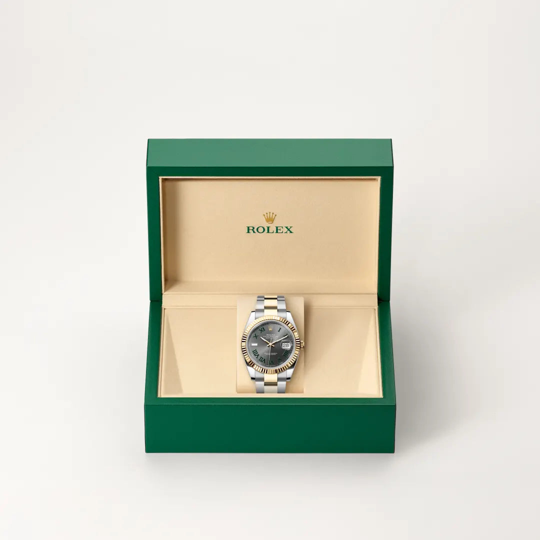Rolex Datejust watch in a green and beige presentation box on a light background.