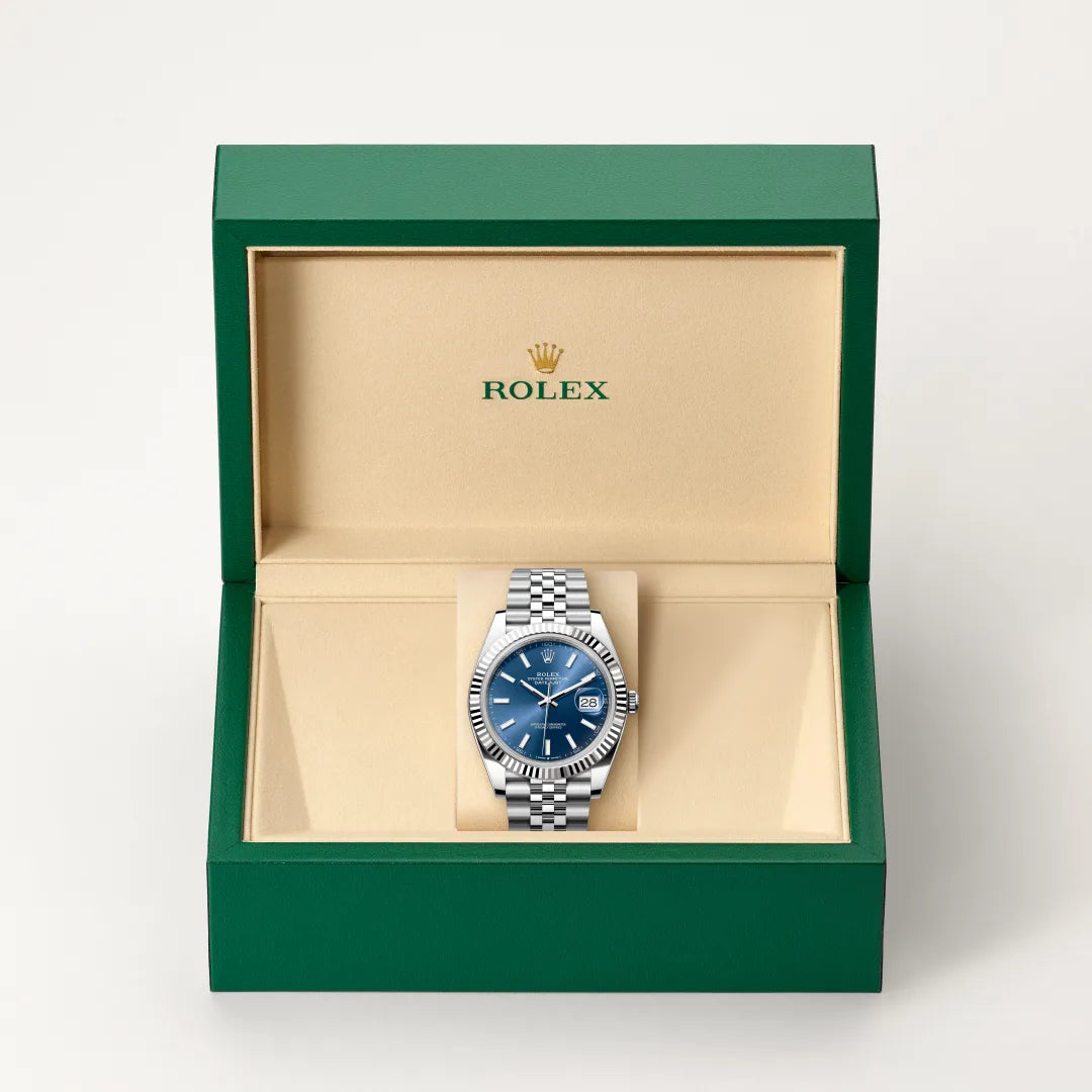 Rolex Datejust watch in a green and beige presentation box on a light background.