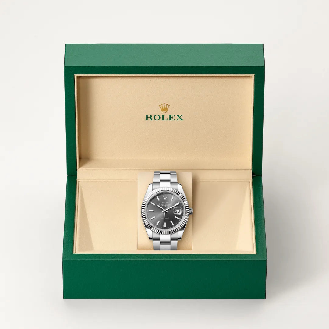Rolex Datejust watch in a green and beige presentation box on a light background.