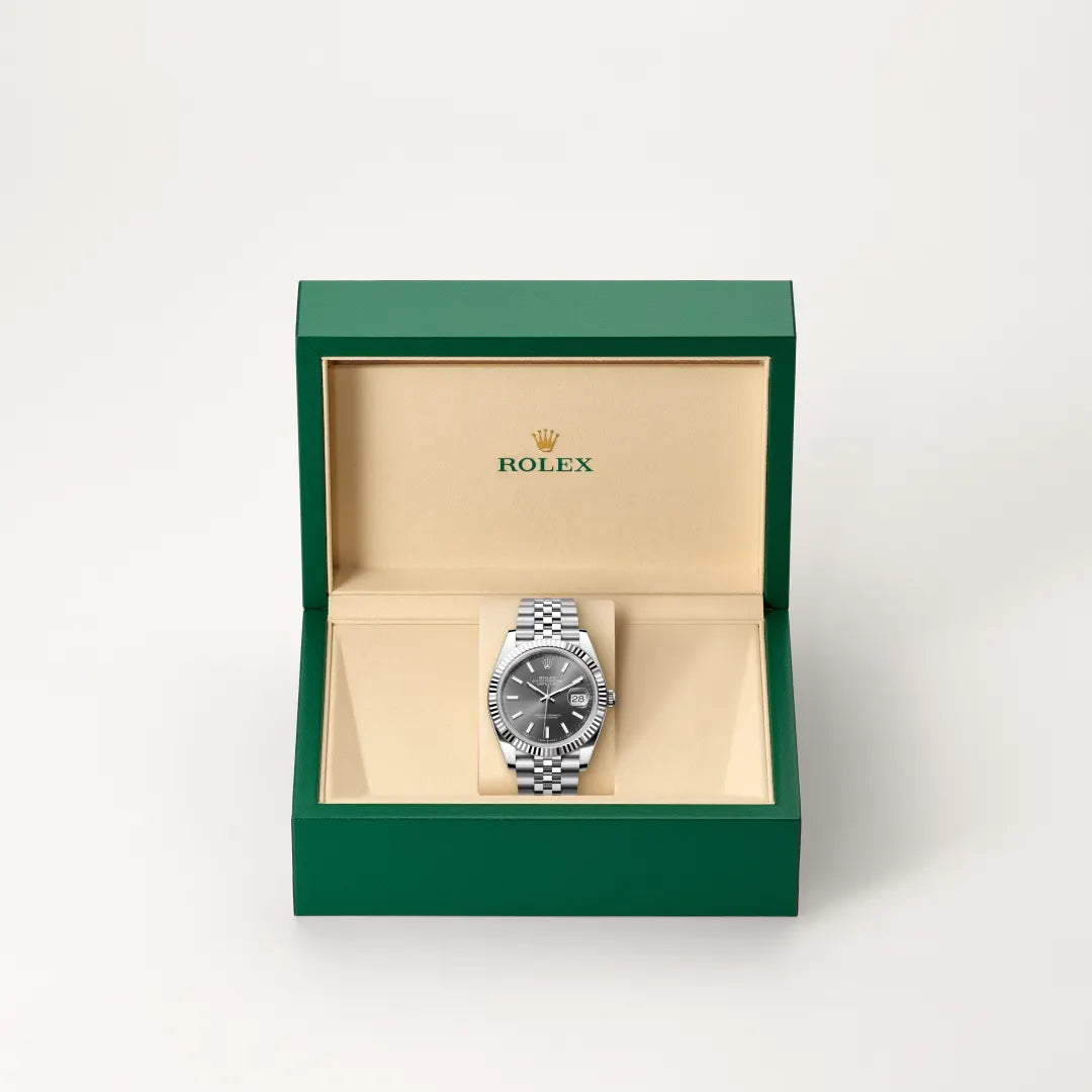 Rolex Datejust watch in a green and beige presentation box on a light background.
