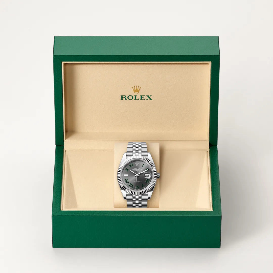 Rolex Datejust watch in a green and beige presentation box on a light background.