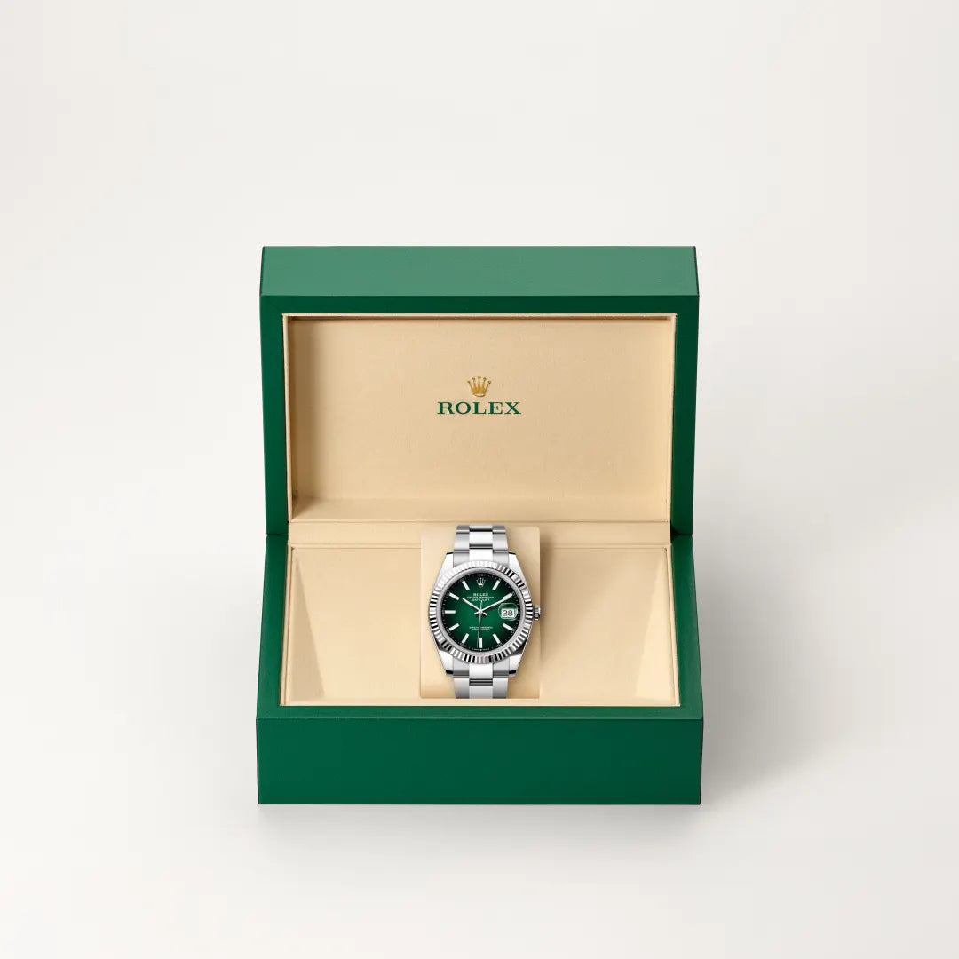 Rolex Datejust watch in a green and beige presentation box on a light background.