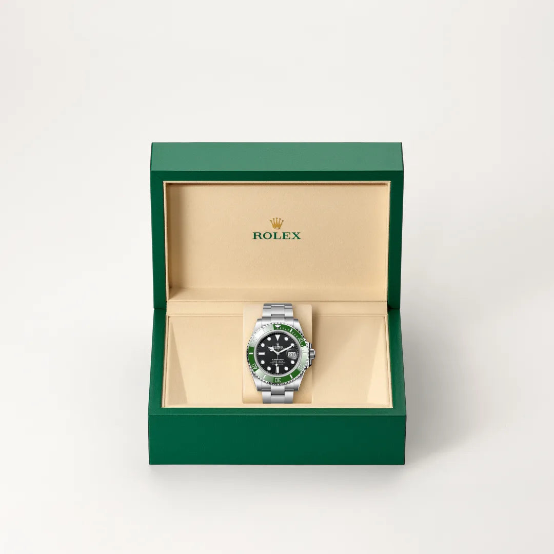 Rolex Submariner Date watch in a green and beige presentation box on a light background.