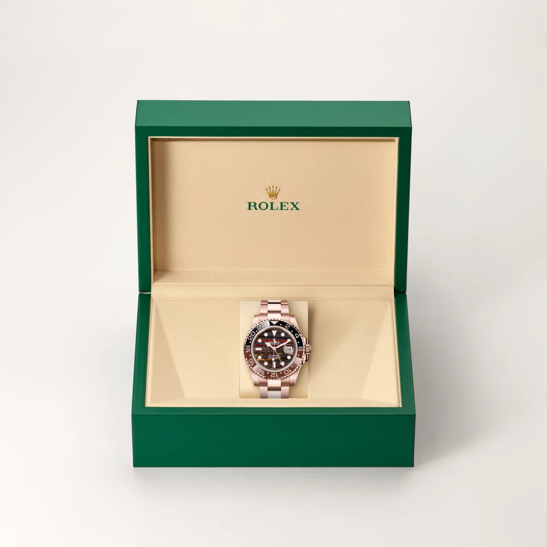 Rolex GMT-Master II watch in a green and beige presentation box on a light background.