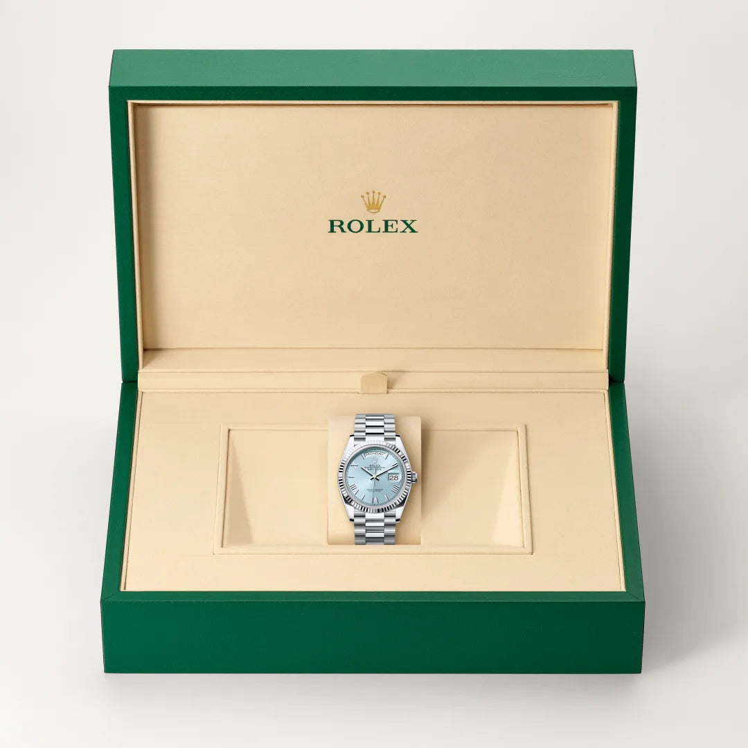 Rolex Day-Date watch in a green and beige presentation box on a light background.