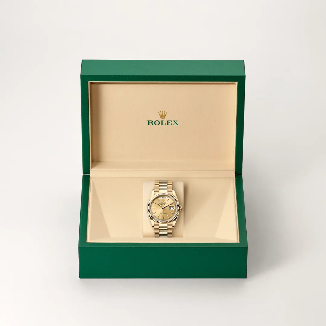 Rolex Day-Date watch in a green and beige presentation box on a light background.