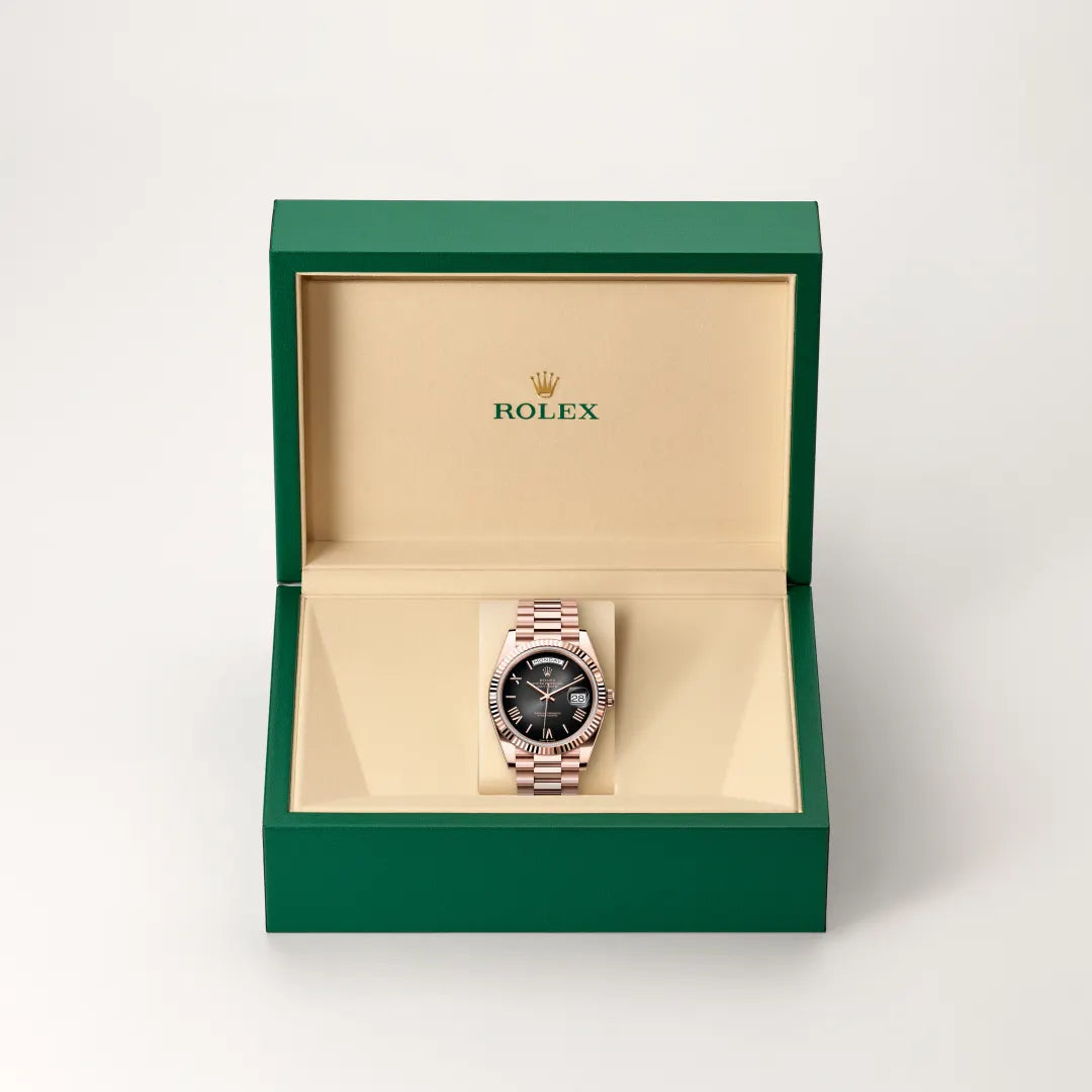 Rolex Day-Date watch in a green and beige presentation box on a light background.