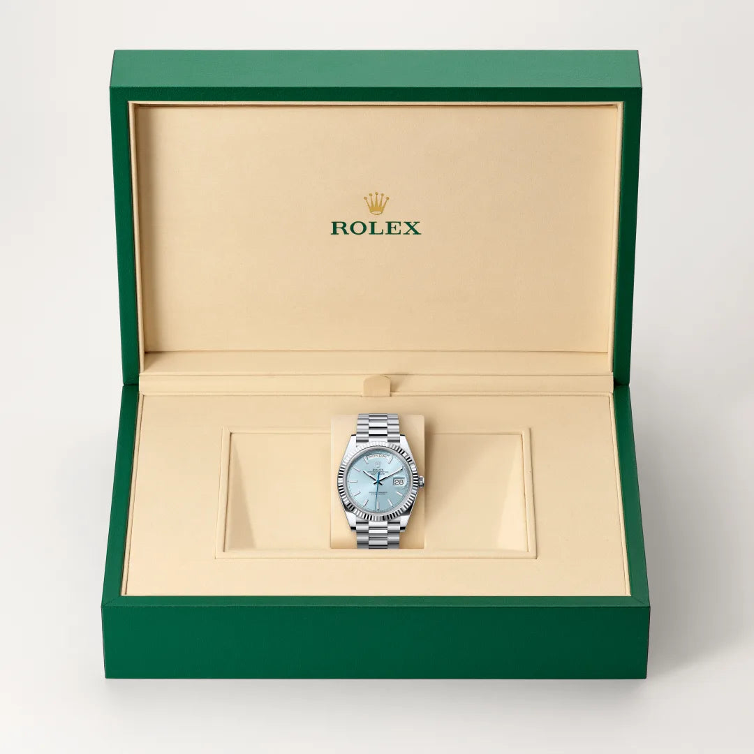 Rolex Day-Date watch in a green and beige presentation box on a light background.