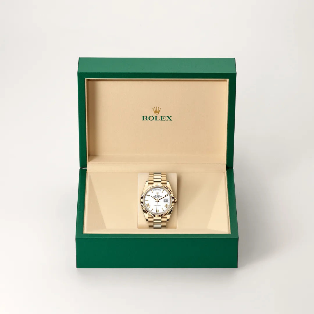 Rolex Day-Date watch in a green and beige presentation box on a light background.