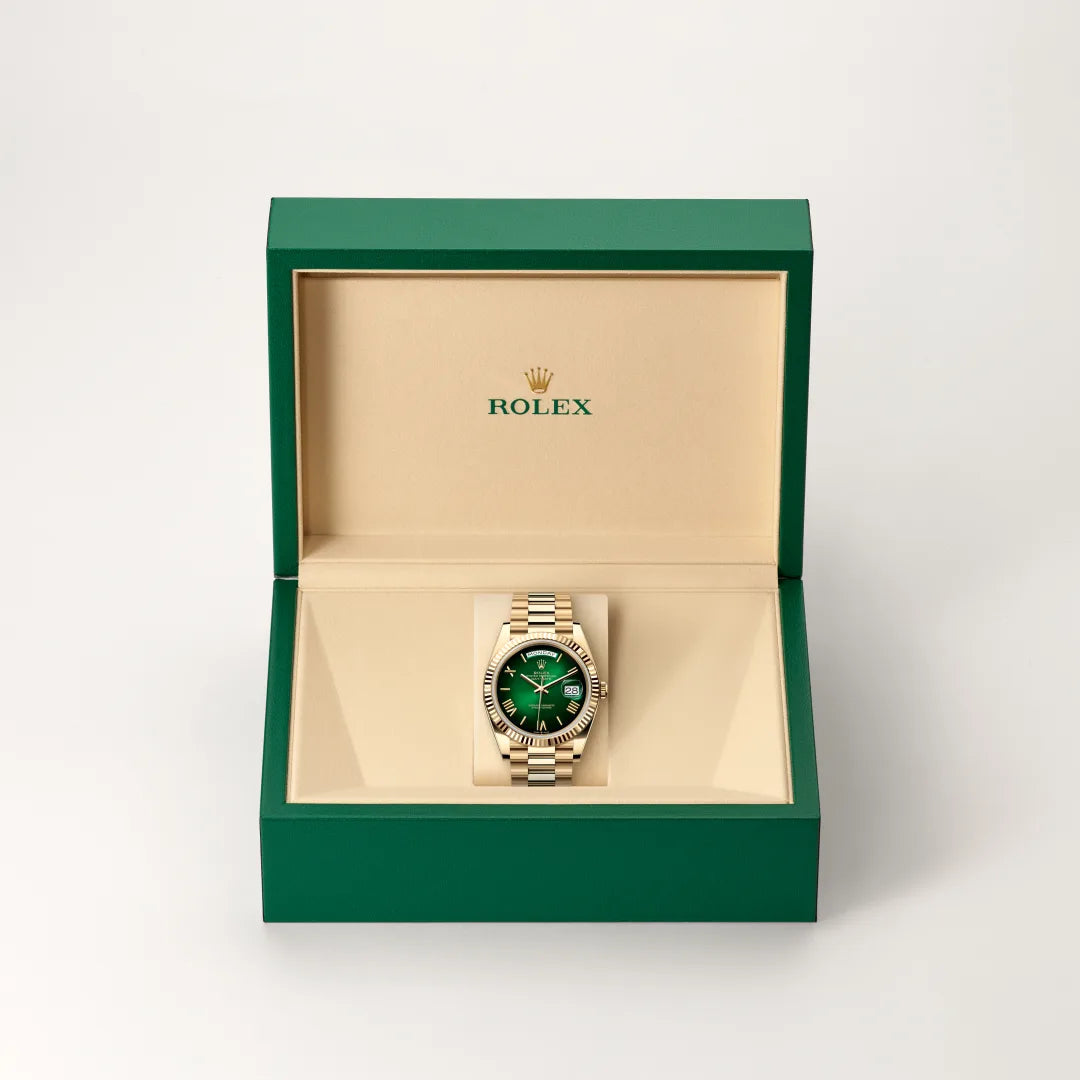 Rolex Day-Date watch in a green and beige presentation box on a light background.