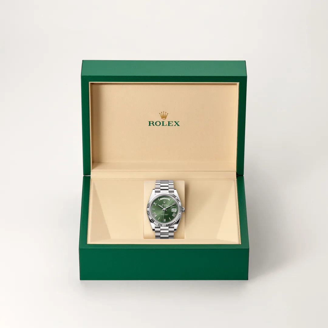 Rolex Day-Date watch in a green and beige presentation box on a light background.