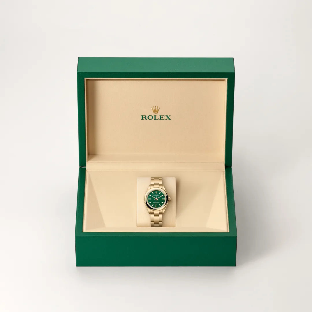 Rolex Oyster Perpetual watch in a green and beige presentation box on a light background.