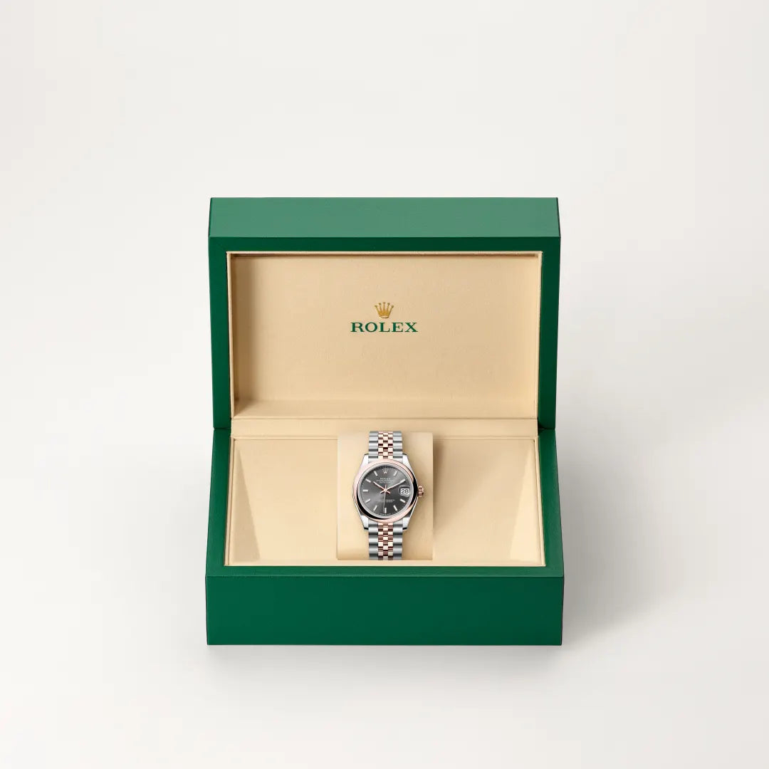 Rolex Datejust watch in a green and beige presentation box on a light background.