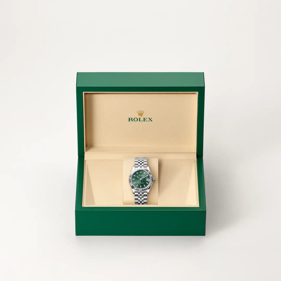 Rolex Datejust watch in a green and beige presentation box on a light background.