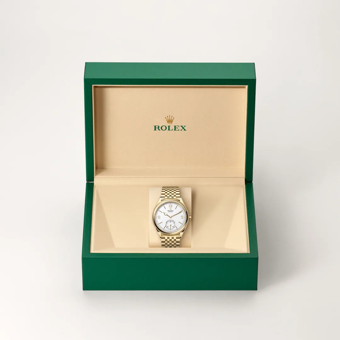 Rolex 1908 watch in a green and beige presentation box on a light background.