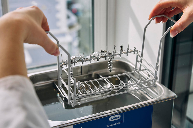 Watch bracelet being dipped into a cleaning solution machine.