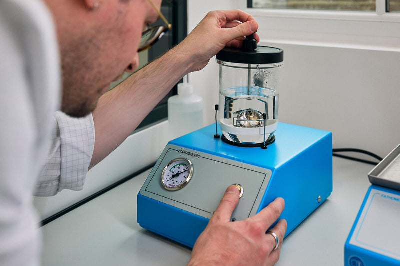 Watchmaker testing the water resistance of a watch.