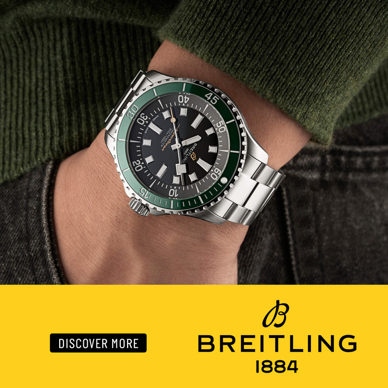 Breitling Superocean watch with a green bezel and steel bracelet on a yellow background with the Breitling logo.