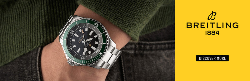 Breitling Superocean watch with a green bezel and steel bracelet on a yellow background with the Breitling logo.