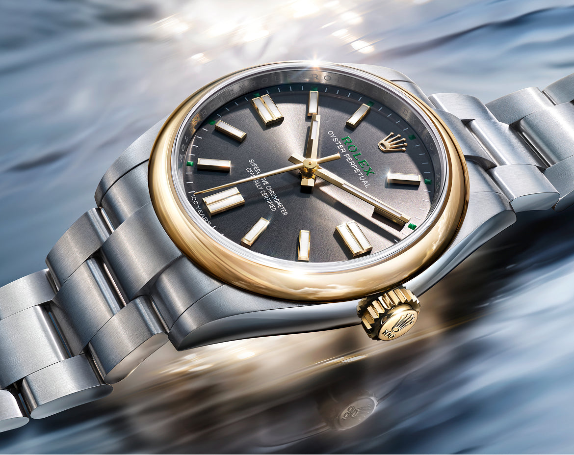 Rolex Oyster Perpetual 41 watch with a gold bezel, steel bracelet, and slate dial on a reflective background.