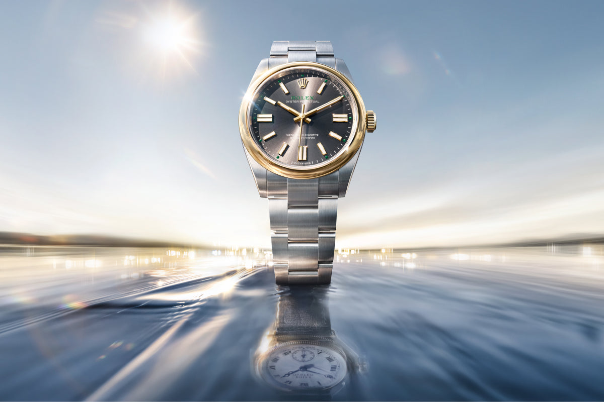 Rolex Oyster Perpetual 41 watch with a gold bezel, steel bracelet, and slate dial on a reflective background.