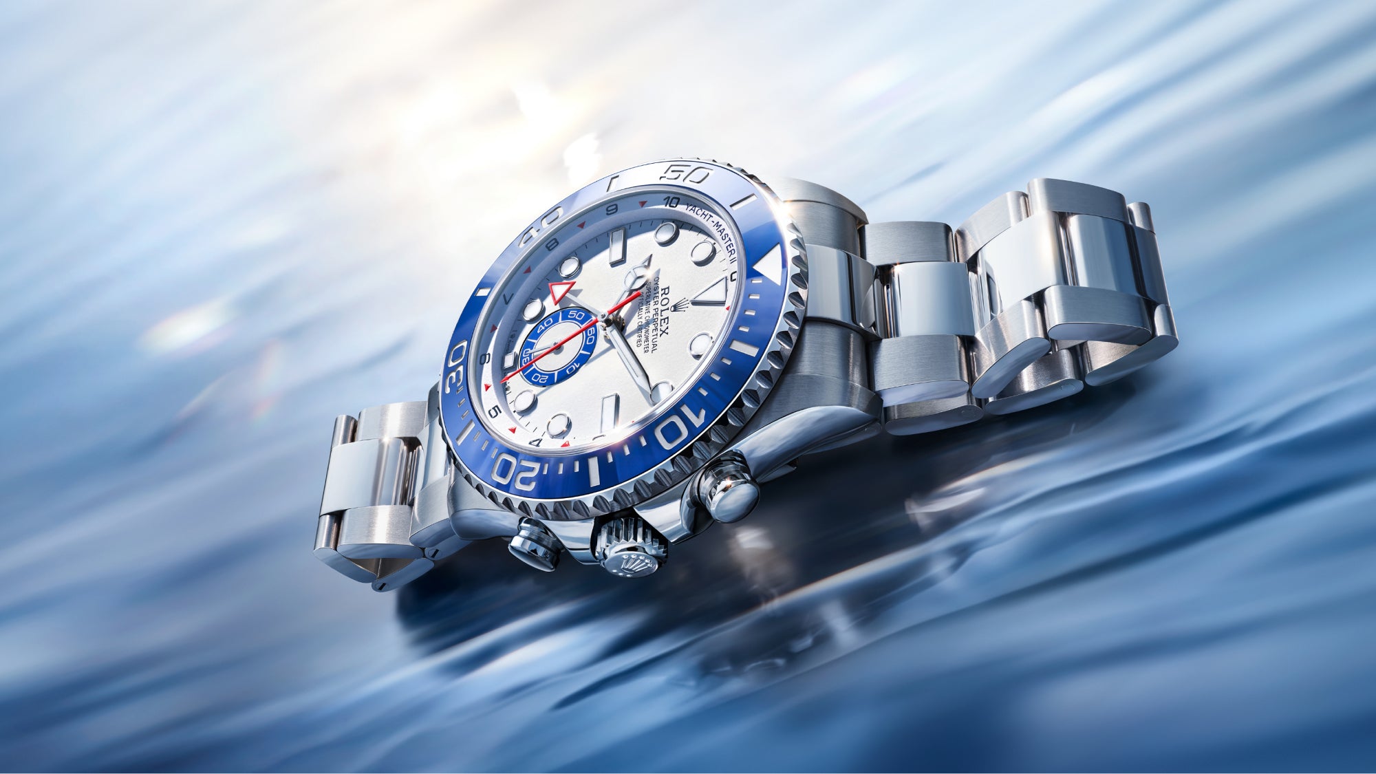Rolex Yacht-Master II with a steel bracelet, blue bezel and white dial on a reflective background.