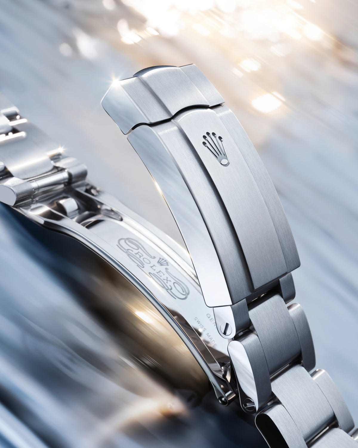 Close-up of a steel Rolex clasp on a reflective background.