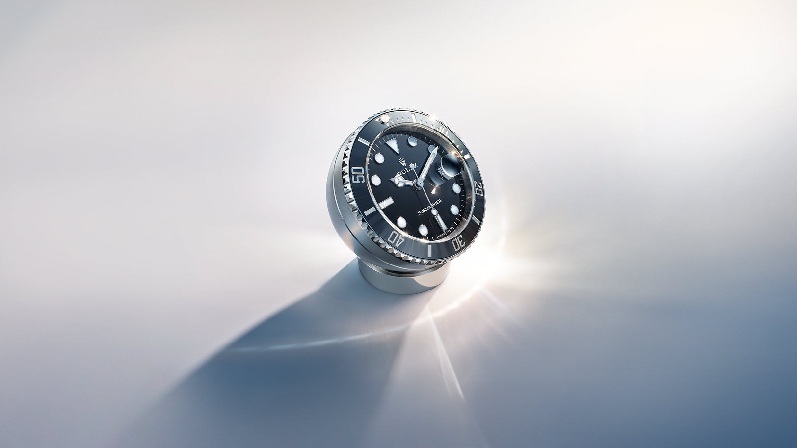 Rolex Submariner Date desk clock on a reflective background.