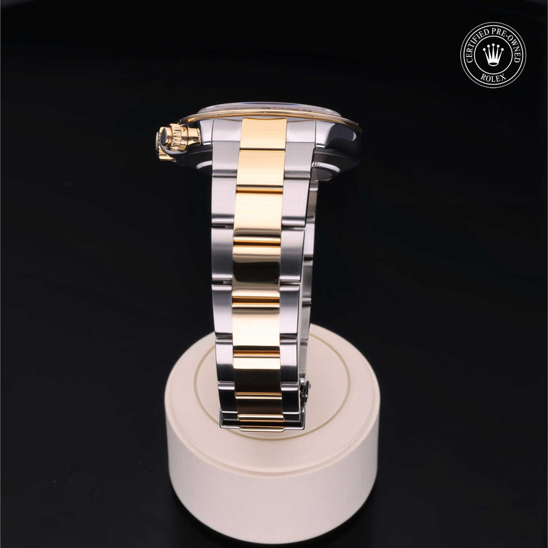 Rolex Cosmograph Daytona with Oystersteel and 18ct yellow gold case, Oyster bracelet & black dial, on a cream presentation stand against a black background.Cosmograph Daytona