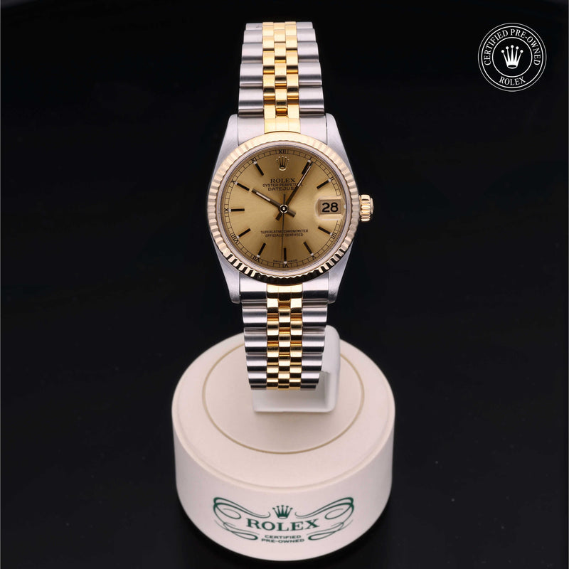Rolex Datejust 31 with steel & yellow-gold Jubilee bracelet and champagne dial, on a cream presentation stand against a black background.Datejust 31