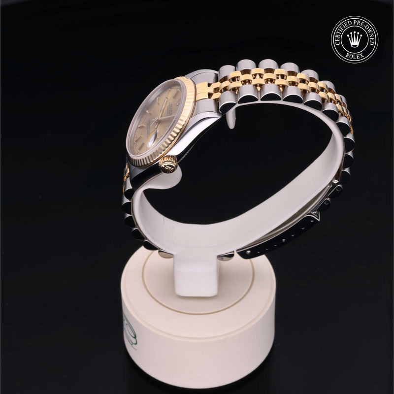 Rolex Datejust 31 with steel & yellow-gold Jubilee bracelet and champagne dial, on a cream presentation stand against a black background.Datejust 31